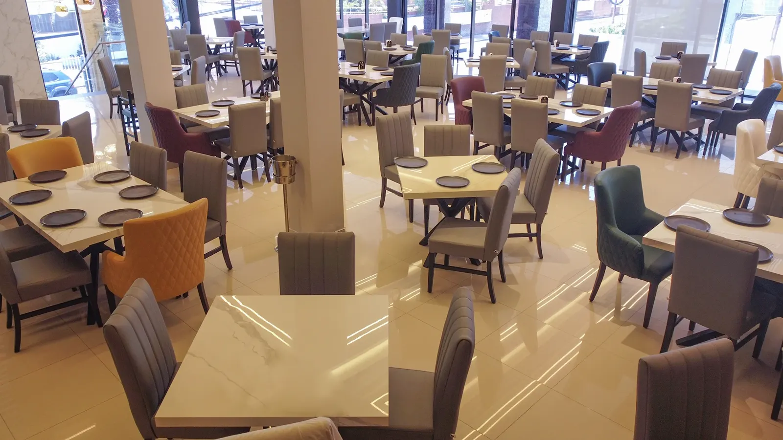 Mesas de mármol y sillas de colores junto a los ventanales del salón